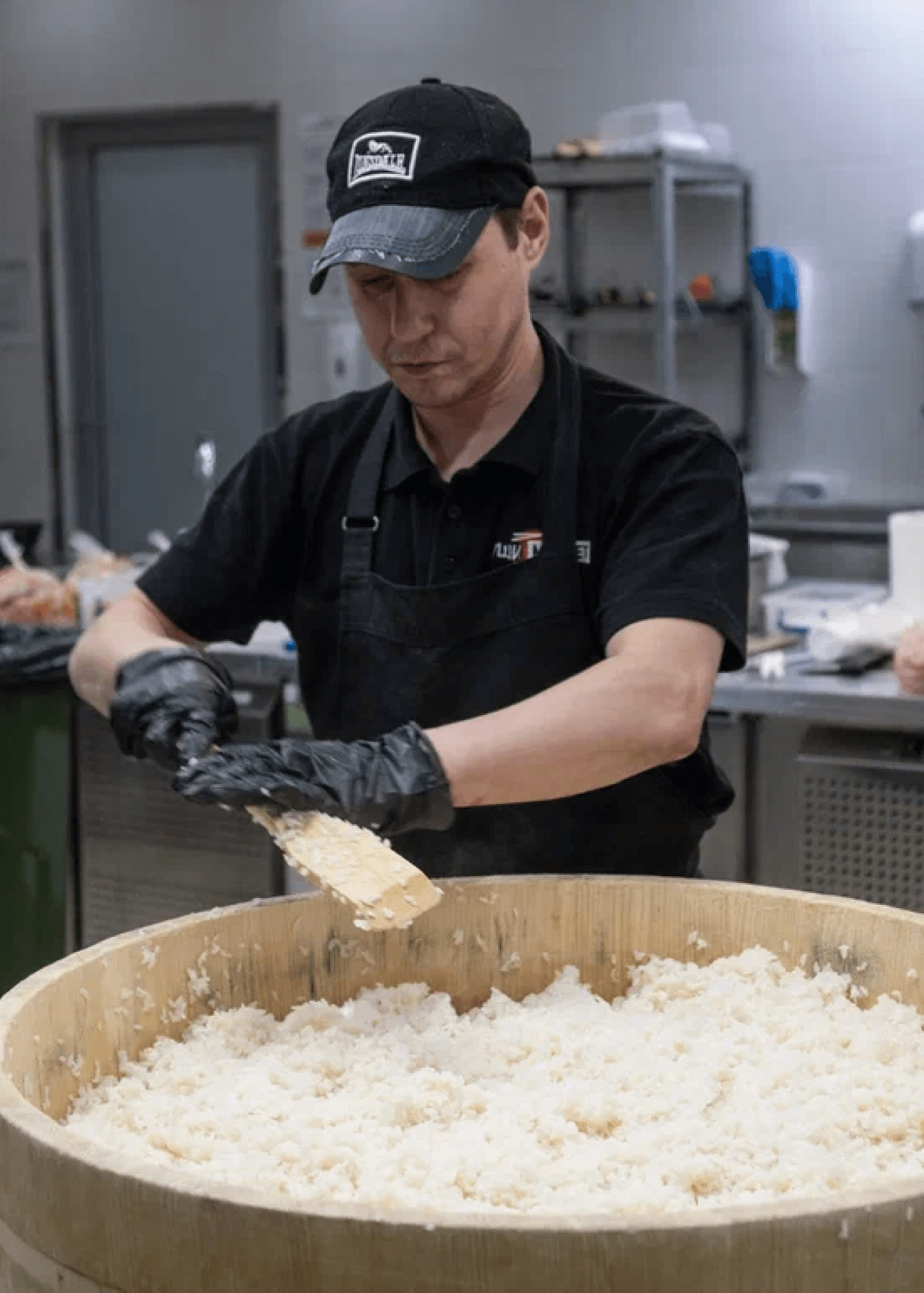 Повар Суши-Маркета смешивает рис с заправкой в кадке